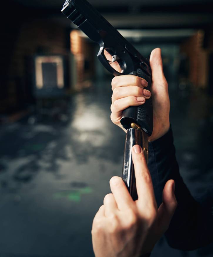 Cropped photo of a skilled female shooter inserting the fully loaded magazine into the mag well